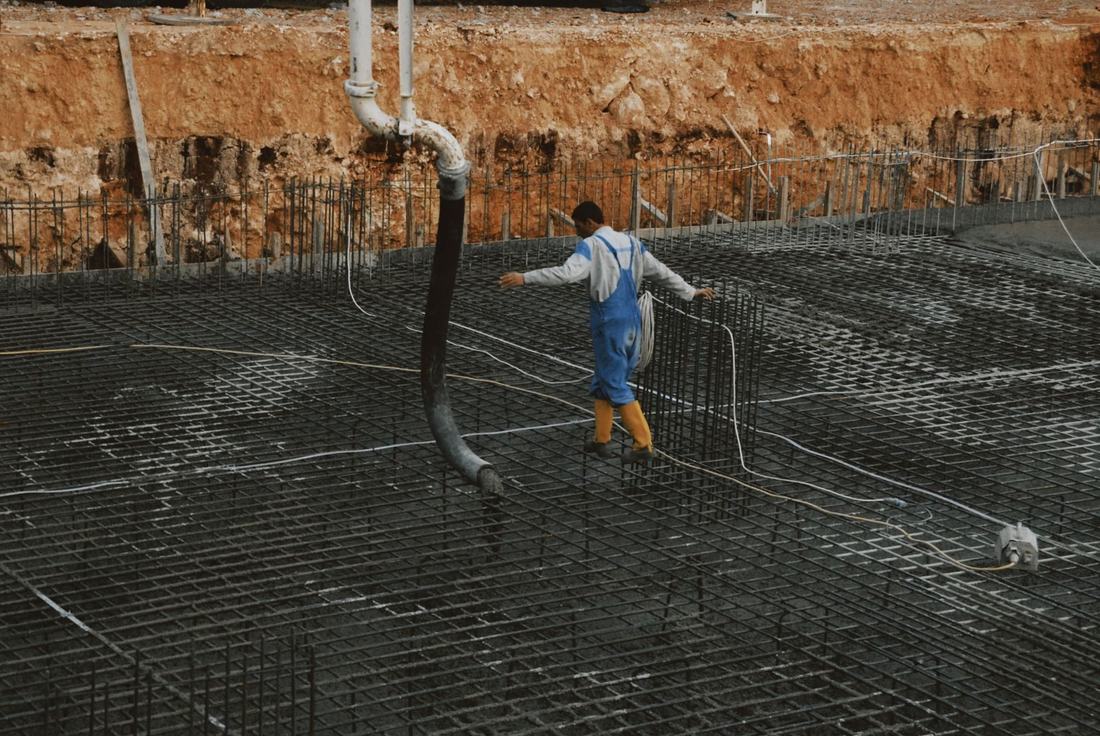 Robotnik na zbrojeniu fundamentu podczas betonowania