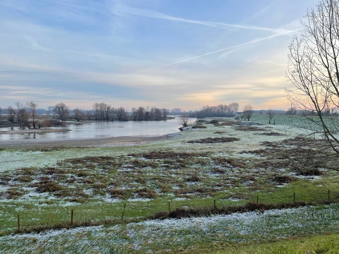 Oszroniona łąka nad rzeką w dolinie o świcie