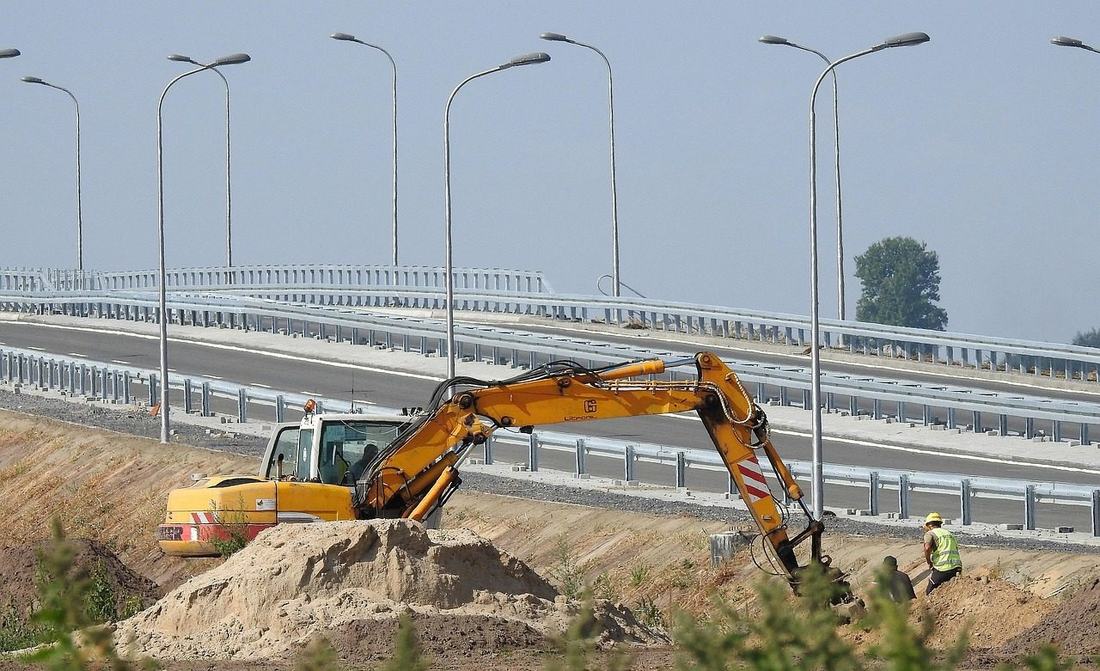Koparka przy budowie drogi obok nowego wiaduktu